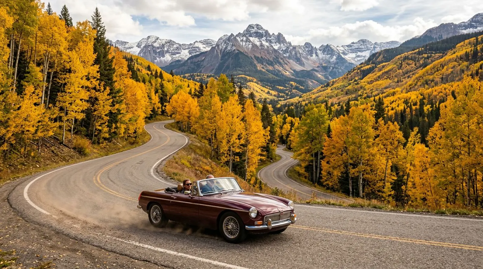 Vintage convertible on a curving mountain road through golden aspens